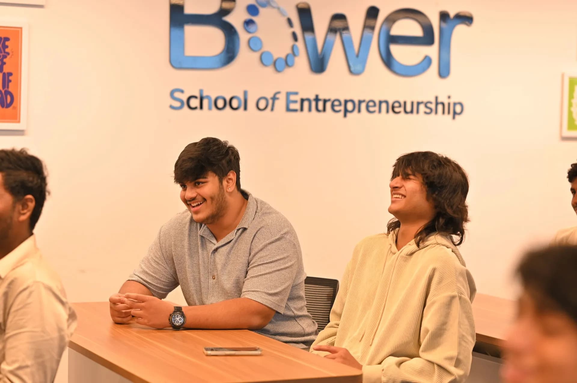 Bower UG students sharing a laugh in class beneath the Bower School of Entrepreneurship sign